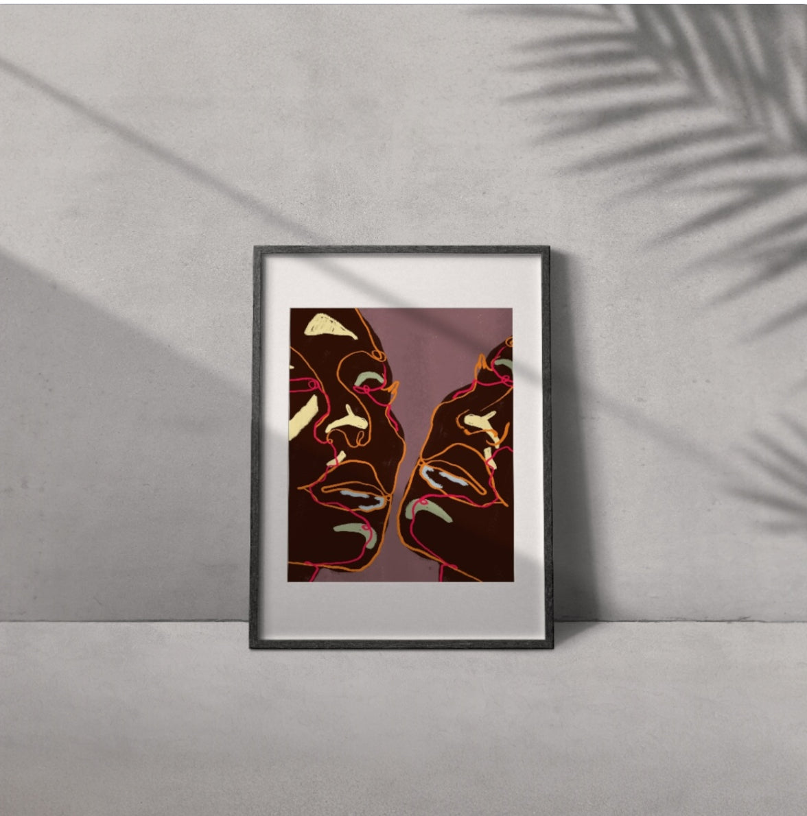 Framed artwork of two abstract faces on a gray wall